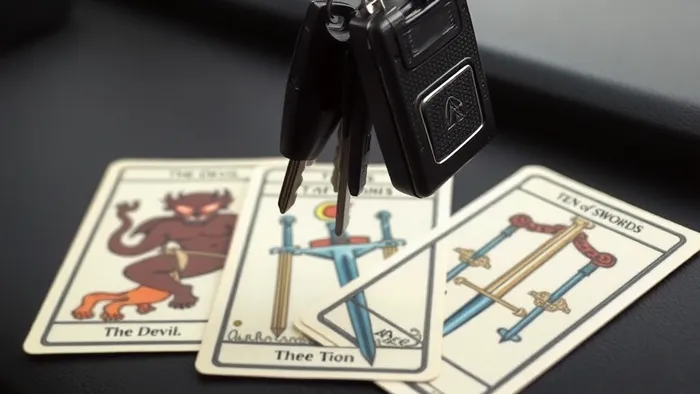 Карты Таро (Дьявол, 10 Мечей, Туз Мечей) на фоне приборной панели автомобиля. Ключи от машины висят над раскладом.