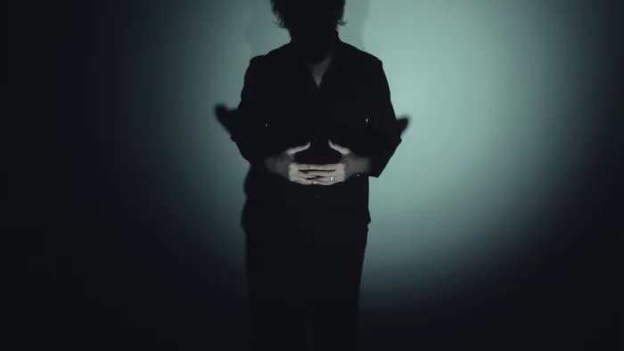 Метафорическое изображение тени человека на стене, которая отличается от его реальной фигуры, символизируя подавленные части личности и влияние прошлого